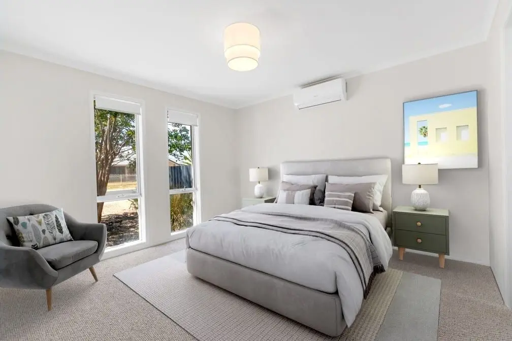 A bedroom at the Peerless Road home, with two tall windows and carpet